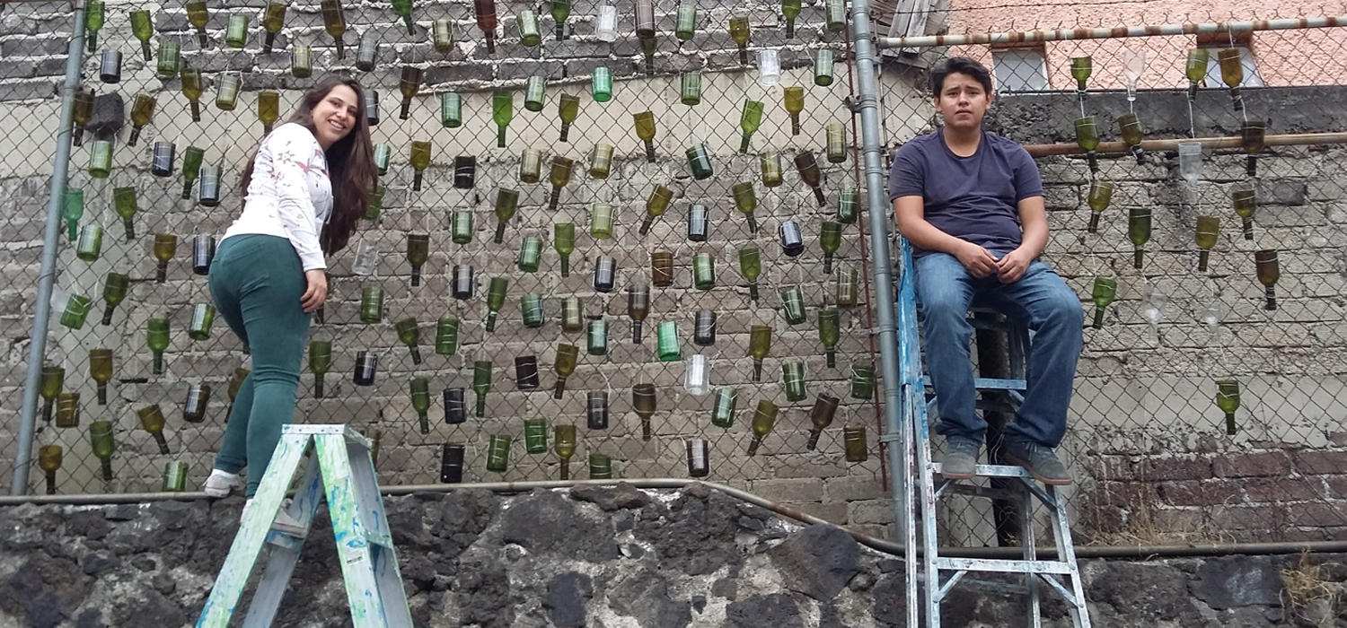 Man and woman on a fence with art from bottles